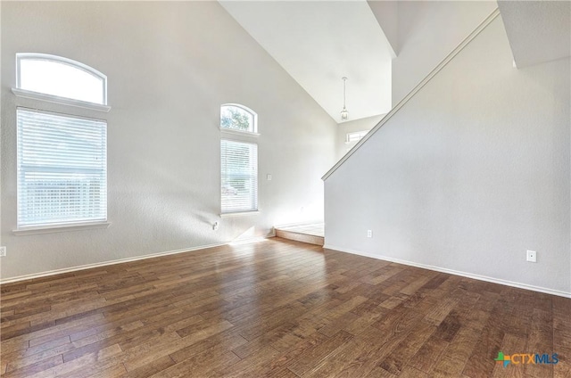 unfurnished living room with dark wood-type flooring and high vaulted ceiling