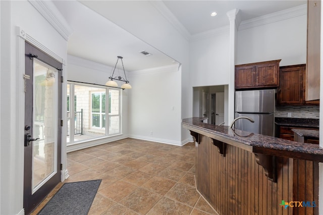 12011 Fm 1150, Luling, TX 78648 - kitchen with a kitchen breakfast bar, freestanding refrigerator, hanging light fixtures, crown molding, and dark stone countertops