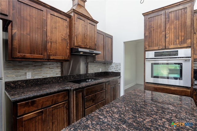 12011 Fm 1150, Luling, TX 78648 - kitchen with stainless steel oven, under cabinet range hood, black electric cooktop, backsplash, and dark stone countertops