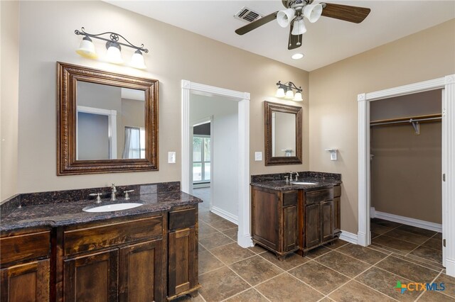 12011 Fm 1150, Luling, TX 78648 - full bathroom featuring ceiling fan, two vanities, a walk in closet, and tile patterned floors