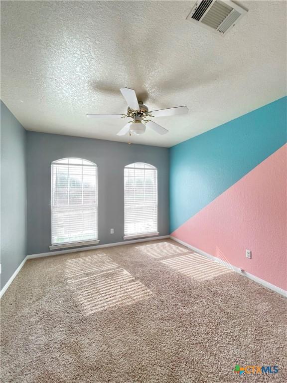 carpeted spare room featuring ceiling fan and a textured ceiling