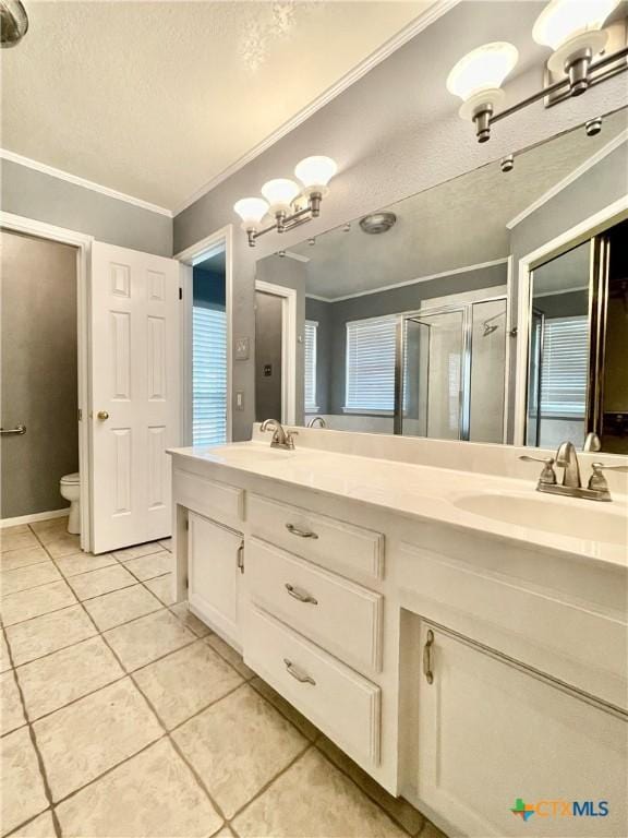 bathroom with vanity, a shower with door, tile patterned floors, crown molding, and toilet