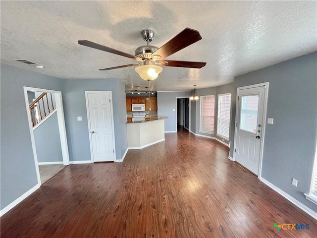 unfurnished living room featuring a textured ceiling, dark hardwood / wood-style flooring, and ceiling fan