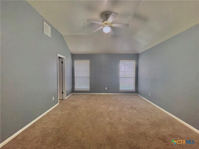 empty room featuring ceiling fan, light colored carpet, a textured ceiling, and vaulted ceiling