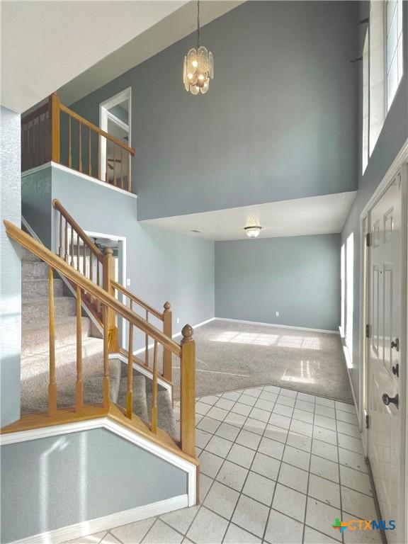 carpeted foyer entrance featuring a chandelier and a towering ceiling