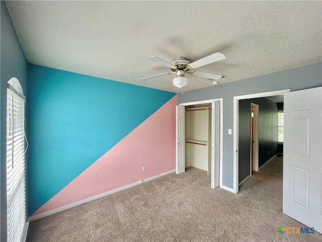 unfurnished bedroom with ceiling fan, a closet, light colored carpet, and a textured ceiling