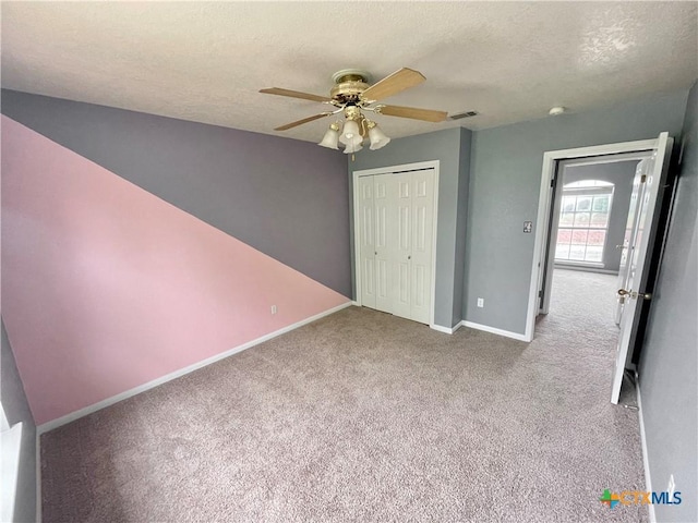 unfurnished bedroom with light carpet, a textured ceiling, a closet, and ceiling fan