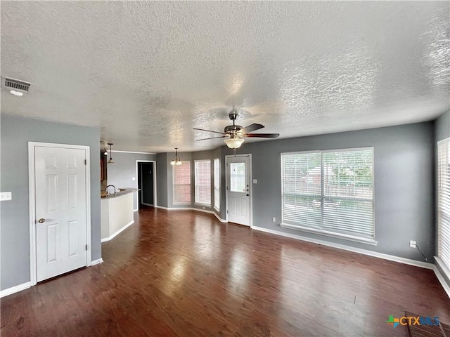 unfurnished living room featuring sink, ceiling fan with notable chandelier, dark hardwood / wood-style flooring, and a textured ceiling