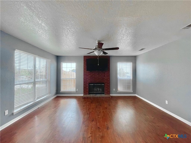 unfurnished living room with ceiling fan, a fireplace, a textured ceiling, and hardwood / wood-style flooring