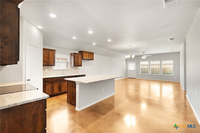 kitchen with ceiling fan with notable chandelier, a center island, a wealth of natural light, and sink