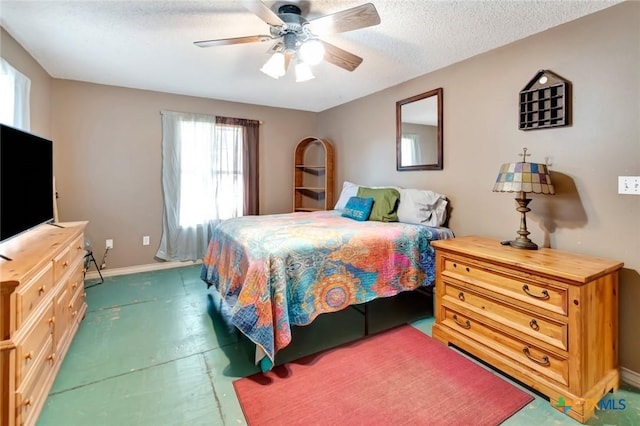 bedroom with a ceiling fan, a textured ceiling, and baseboards