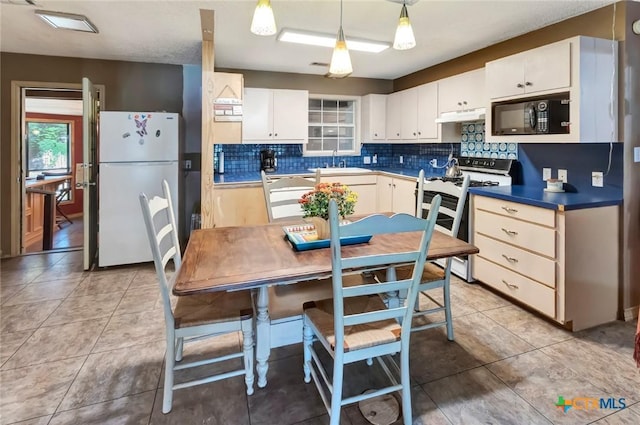 kitchen featuring range with gas stovetop, freestanding refrigerator, under cabinet range hood, black microwave, and a sink