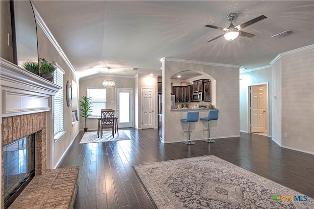 living room featuring dark wood-type flooring, visible vents, a fireplace, and crown molding