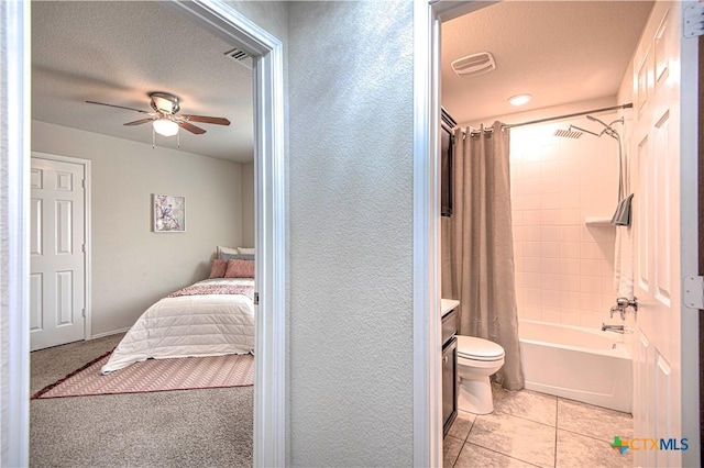 ensuite bathroom featuring visible vents, a ceiling fan, toilet, shower / bathtub combination with curtain, and a textured ceiling