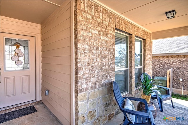 entrance to property featuring brick siding and a porch