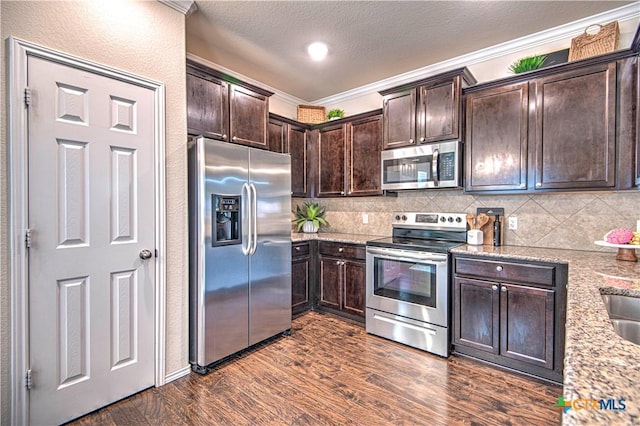kitchen with crown molding, tasteful backsplash, dark brown cabinets, stainless steel appliances, and dark wood-type flooring