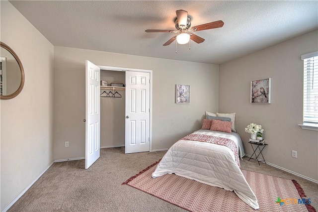 carpeted bedroom with a closet, ceiling fan, a textured ceiling, and baseboards