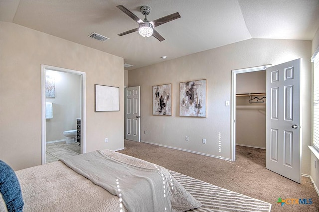 bedroom with lofted ceiling, visible vents, a walk in closet, and connected bathroom