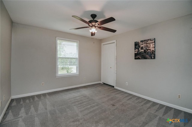 carpeted empty room with baseboards and a ceiling fan