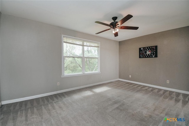 carpeted spare room with a ceiling fan and baseboards