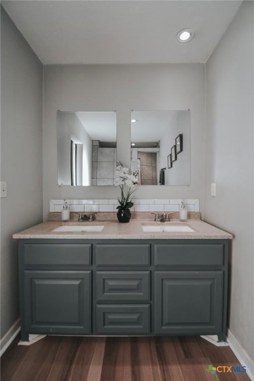 bathroom with decorative backsplash, baseboards, a sink, and double vanity