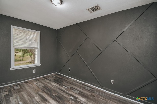 empty room with visible vents and dark wood-style flooring