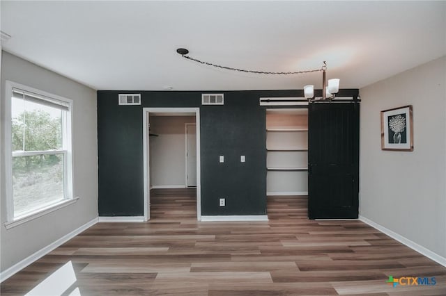 interior space with wood finished floors, visible vents, baseboards, and an inviting chandelier