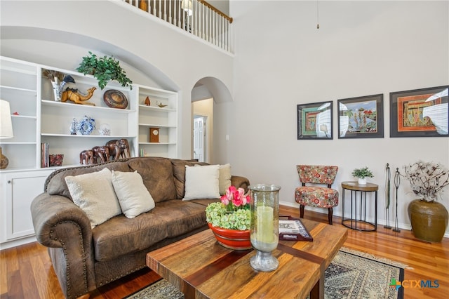 8713 Blackvireo Dr, Austin, TX 78729 - living room featuring baseboards, arched walkways, a high ceiling, and wood finished floors