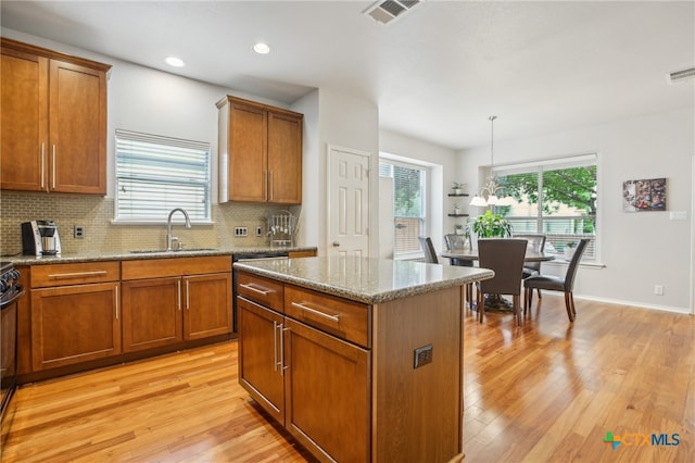 8713 Blackvireo Dr, Austin, TX 78729 - kitchen with visible vents, brown cabinetry, tasteful backsplash, a sink, and light wood finished floors