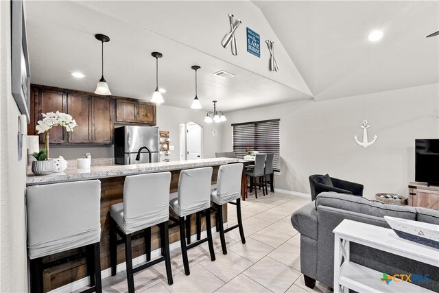 2319 Westview Dr, Canyon Lake, TX 78133 - kitchen featuring hanging light fixtures, a breakfast bar area, dark brown cabinetry, visible vents, and freestanding refrigerator
