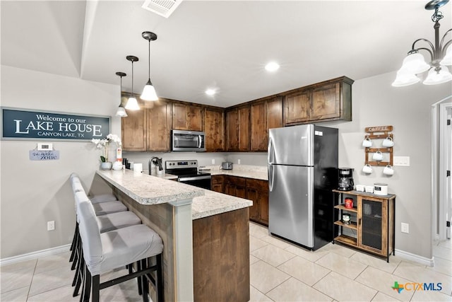 2319 Westview Dr, Canyon Lake, TX 78133 - kitchen with light tile patterned floors, light countertops, a peninsula, appliances with stainless steel finishes, and visible vents