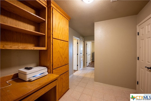 hallway featuring a textured ceiling and light tile patterned floors