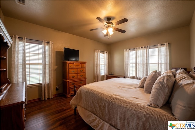 bedroom featuring dark wood-type flooring, ceiling fan, and a textured ceiling