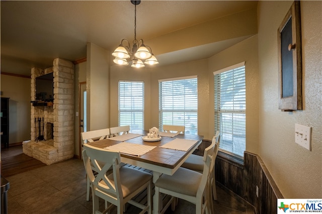 dining area featuring dark tile patterned floors, an inviting chandelier, and a fireplace