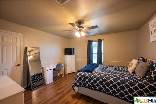 bedroom featuring dark wood-type flooring, a textured ceiling, and ceiling fan