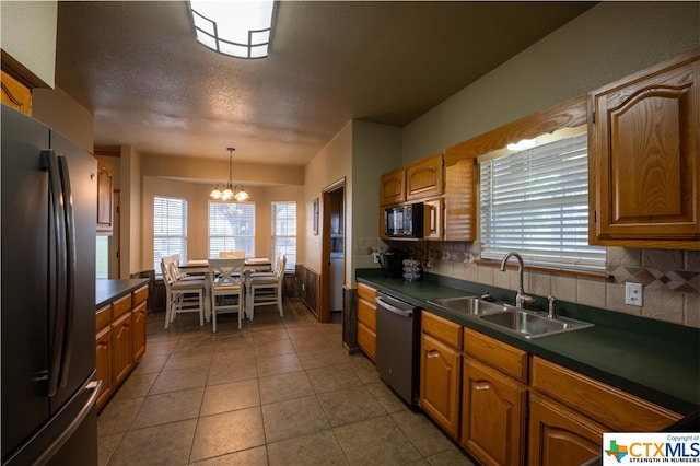 kitchen featuring stainless steel appliances, an inviting chandelier, a textured ceiling, sink, and tasteful backsplash