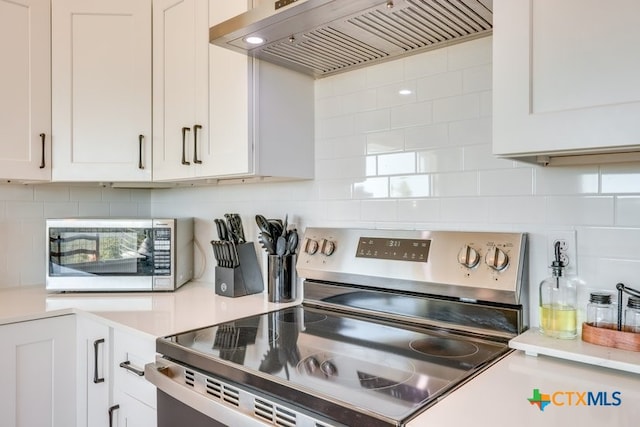 482 Dusty Saddle, Canyon Lake, TX 78133 - kitchen featuring stainless steel appliances, custom range hood, white cabinets, and tasteful backsplash
