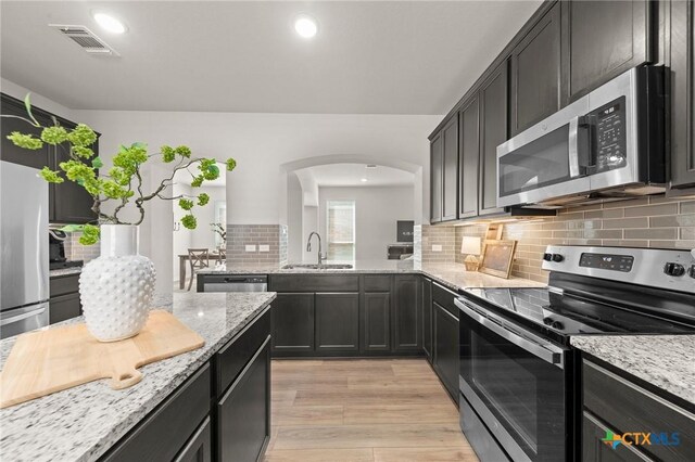 1044 Shelby Dr, Belton, TX 76513 - kitchen with visible vents, a sink, stainless steel appliances, arched walkways, and light stone countertops