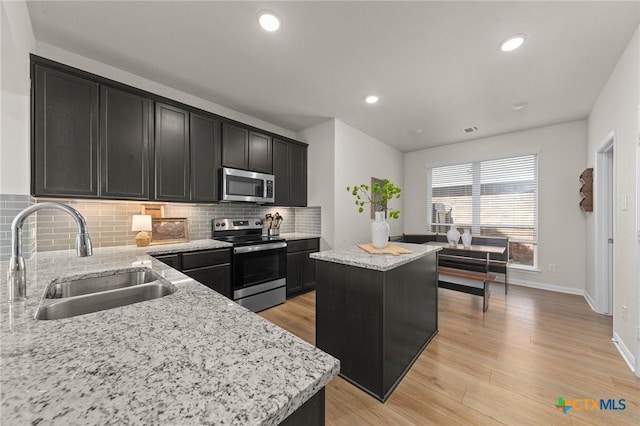 1044 Shelby Dr, Belton, TX 76513 - kitchen featuring dark cabinetry, a sink, appliances with stainless steel finishes, light wood-type flooring, and a center island