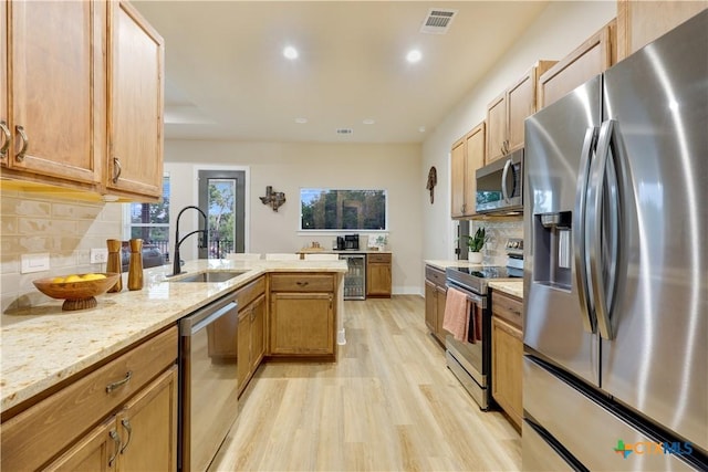 kitchen with backsplash, sink, light hardwood / wood-style floors, light stone counters, and stainless steel appliances