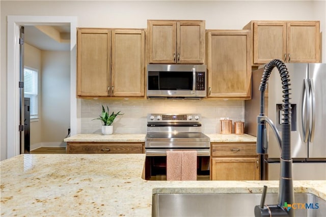 kitchen with decorative backsplash, light stone counters, and appliances with stainless steel finishes