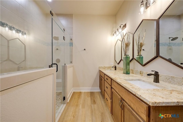 bathroom with a shower with shower door, wood-type flooring, and vanity