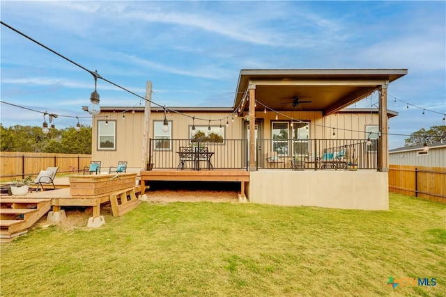 rear view of property with a lawn, ceiling fan, and a wooden deck