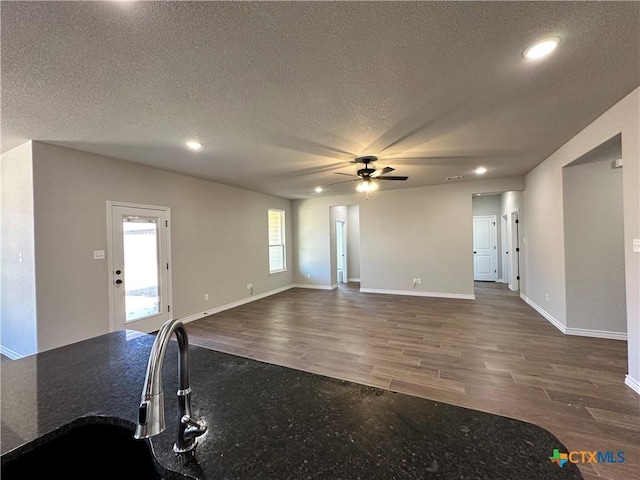 unfurnished living room with ceiling fan, wood finished floors, a textured ceiling, recessed lighting, and baseboards
