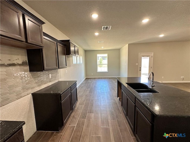 kitchen featuring a sink, a textured ceiling, dark wood-style floors, recessed lighting, and decorative backsplash