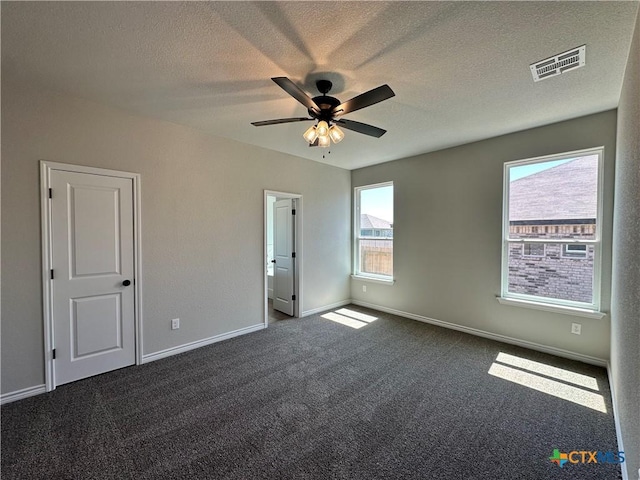 unfurnished bedroom with dark colored carpet, baseboards, a textured ceiling, and a ceiling fan