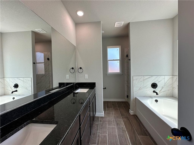 bathroom with a stall shower, a garden tub, double vanity, and baseboards