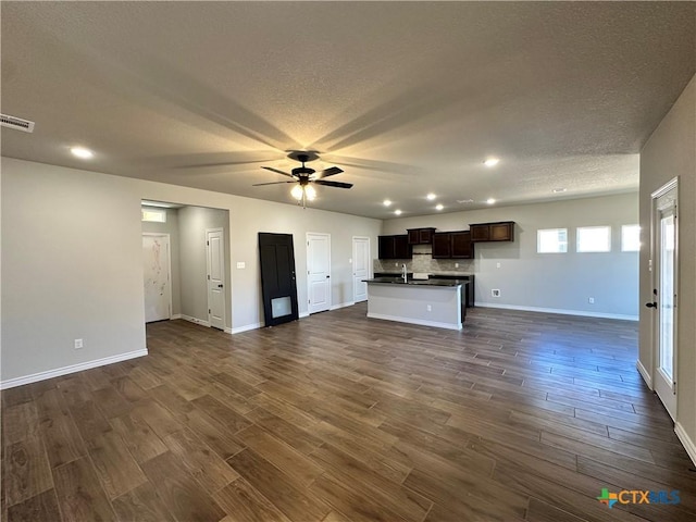 unfurnished living room featuring a ceiling fan, dark wood-style floors, baseboards, a textured ceiling, and recessed lighting