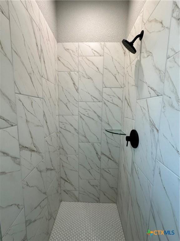 full bathroom with a tile shower and a textured wall