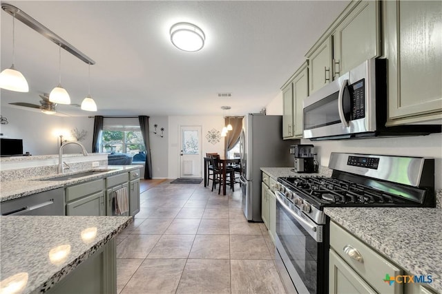 kitchen with light stone countertops, visible vents, appliances with stainless steel finishes, a sink, and decorative light fixtures